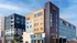 Modern urban complex featuring stylish mixed-use buildings with sleek designs, large windows, and individual balconies, set against a clear blue sky.