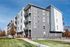 Contemporary apartment building with modern design, featuring sleek balconies and a vibrant exterior, set against a clear blue sky.