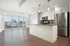 Bright and modern open-concept kitchen and living area with stainless steel appliances and large windows offering a beautiful view.