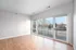 Bright and airy room with sleek wooden floors and expansive glass doors leading to a private balcony, offering serene outdoor views.