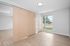 Bright and inviting room with sleek wooden flooring, a large window offering natural light, and a modern sliding door adding a touch of elegance.