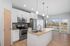 Modern kitchen with sleek appliances, granite countertops, and elegant pendant lighting, offering a bright and open space with scenic outdoor views.