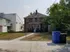 Charming brick duplex with inviting entry, nestled in a serene suburban setting with lush greenery and ample space.