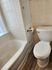 Charming bathroom featuring elegant white tiles, a pristine bathtub, and a modern toilet, providing a cozy and refreshing space.