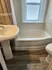 Charming bathroom with elegant fixtures, featuring a pristine bathtub and sleek pedestal sink under a bright window.