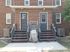 Charming brick duplex with twin staircases, stylish grey doors, and elegant window symmetry.