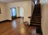 Inviting living area with elegant wood flooring and a cozy staircase leading upstairs, enhanced by natural light through charming draped windows.