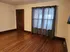 Inviting room with elegant hardwood floors, warm wooden door, and large window with soft curtains enhancing natural light.