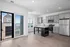 Modern kitchen with sleek stainless steel appliances, spacious gray cabinetry, and large windows offering a scenic urban view.