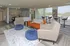 Modern lounge area with vibrant orange sofa, plush armchairs, and sleek high-top tables, offering a stylish and inviting space.