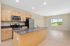 Bright open-concept kitchen with modern stainless steel appliances and large island, seamlessly flowing into a sunlit living area with scenic window views.