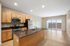 Modern open-concept kitchen with granite countertops and stainless steel appliances, leading to a bright living area with large sliding glass doors.