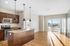 Modern open-concept kitchen and living area with sleek appliances, elegant wooden cabinetry, and large windows offering abundant natural light.
