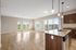 Bright open-plan living space with large windows, modern hardwood floors, and stylish kitchen island with granite countertops.
