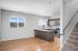 Modern open-concept kitchen with sleek countertops, stainless steel appliances, and elegant pendant lighting, adjacent to a sunlit living area with beautiful hardwood floors.