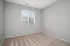 Bright, empty room with neutral-toned carpet and a large window offering natural light.