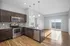 Modern kitchen with sleek cabinetry, stainless steel appliances, and an island, flowing into a bright living area with large sliding doors to a balcony.