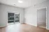 Bright empty room featuring beautiful wood flooring, large sliding glass doors leading to a balcony, and a cozy adjacent carpeted space.