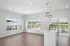 Bright, open-concept apartment with floor-to-ceiling windows, modern lighting, and a stylish kitchen island with sink, overlooking peaceful views.