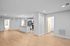 Modern open-concept apartment interior with sleek kitchen island, light wood flooring, and spacious rooms.