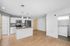 Modern open-concept kitchen and living area with sleek appliances, hardwood flooring, and convenient in-unit laundry.