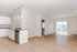 Modern open-plan kitchen and living area with ample natural light and sleek finishes, highlighting hardwood floors and contemporary design.