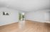 Bright living room with elegant hardwood floors, large sliding glass doors leading to a balcony, and a neutral color palette for a spacious feel.