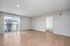 Bright and spacious living room with modern wooden flooring, large windows offering plenty of natural light and a view of the surrounding area, leading to a cozy adjacent room.