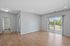 Bright and airy living space with large sliding glass doors leading to a balcony, featuring modern hardwood floors and soft gray walls.
