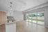 Bright, open-concept living and kitchen area with large windows, stylish pendant lighting, and modern fixtures.