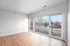 Bright and airy empty room with large windows and hardwood flooring, leading to a spacious balcony with scenic views.
