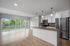 Modern open-concept apartment with sleek kitchen, stainless steel appliances, and large windows overlooking lush greenery.