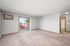 Bright and spacious living room with plush carpeting, large window, and sliding glass door opening to a private balcony.