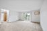 Spacious living room with plush carpet, sliding glass doors leading to a balcony with scenic views.
