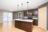 Modern kitchen with sleek countertops, stainless steel appliances, and elegant pendant lighting, opening to a bright living area with sliding glass doors.