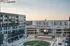 Vibrant urban complex with a modern residential building overlooking an inviting plaza and entertainment stage at sunset.
