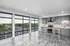 Modern open-concept kitchen with panoramic floor-to-ceiling windows and sleek gray cabinetry, offering a bright and inviting space with scenic views.