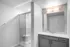 Modern bathroom with sleek glass shower and elegant vanity mirror under soft lighting.