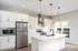 Modern kitchen with sleek white cabinetry, stainless steel appliances, and elegant pendant lighting over a central island.