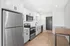 Modern kitchen with sleek stainless steel appliances, white cabinetry, and elegant wood flooring.