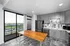 Modern kitchen with sleek gray cabinetry, stainless steel appliances, a wooden island, and large windows overlooking a vibrant cityscape.