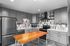 Modern kitchen with sleek gray cabinets, stainless steel appliances, stylish tile backsplash, and a warm wood island.