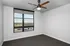 Bright, spacious room with a ceiling fan and large window offering a scenic view of surrounding rooftops and landscape.