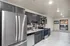 Modern kitchen with stainless steel appliances, dark cabinetry, and sleek tiled backsplash in an open-concept layout.