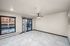 Modern apartment interior featuring large windows, sleek marble floors, and a ceiling fan, offering a bright and open living space with city views.