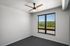 Bright bedroom with large window and modern ceiling fan, offering serene outdoor views.
