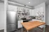 Modern kitchen with stainless steel appliances, stylish gray tile backsplash, and sleek wooden island creating a contemporary space.