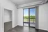 Bright apartment interior with large sliding glass doors opening to a balcony with a scenic view, featuring modern gray flooring and an inviting open space.