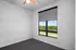 Bright, modern bedroom with a large window offering serene green views, complete with a stylish ceiling fan.