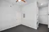 Modern room with sleek built-in laundry area, featuring a stacked washer and dryer alongside a spacious carpeted area.